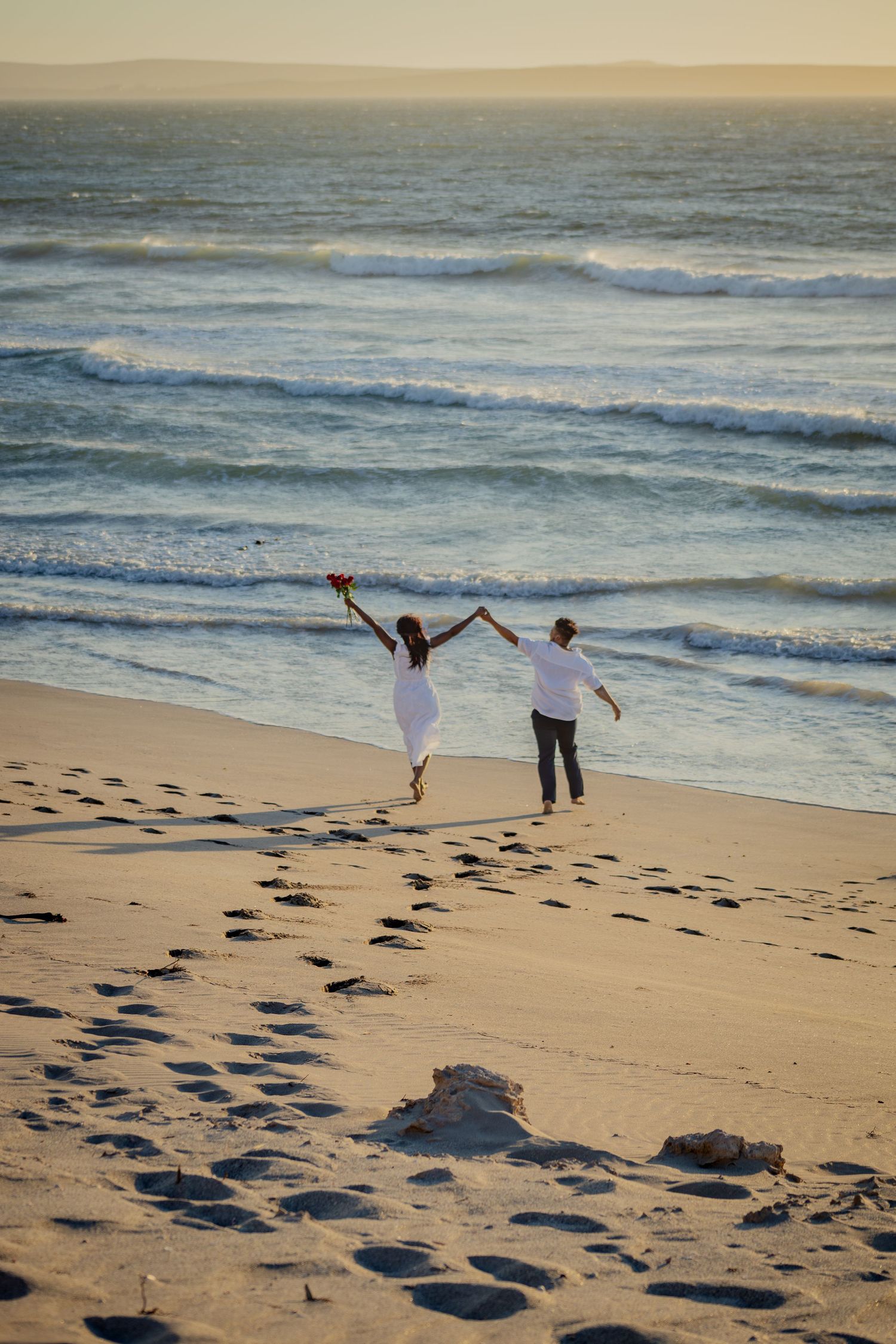 Couple running hand in hand on the shoreline