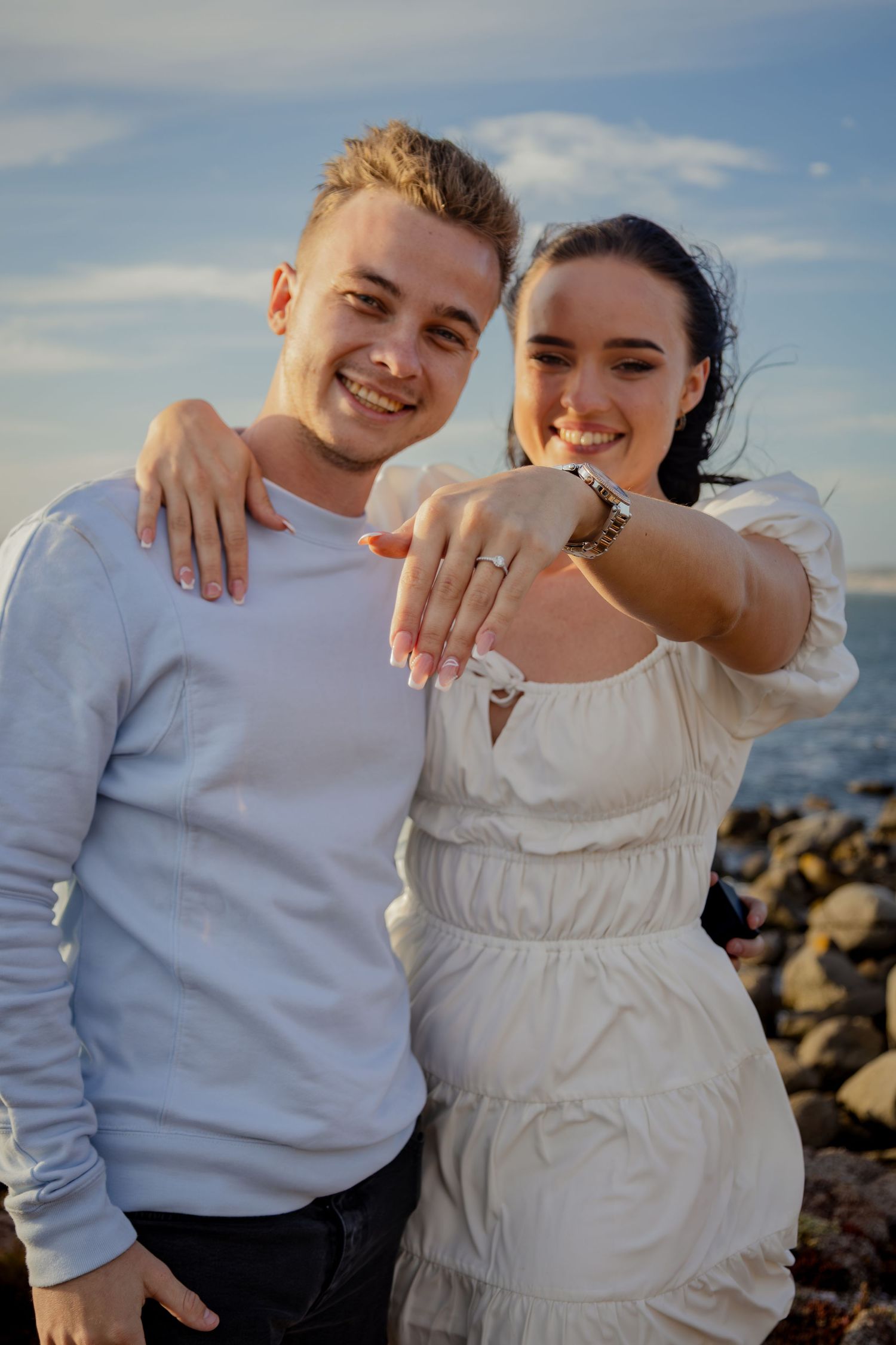 Couple showing an engagement ring on the beach