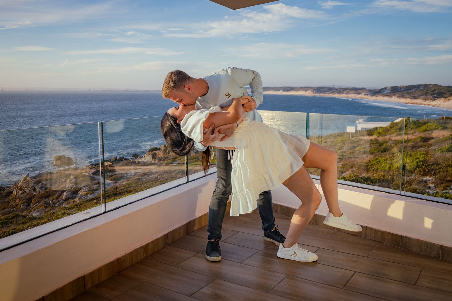 Couple sharing a dip kiss on a balcony over the ocean