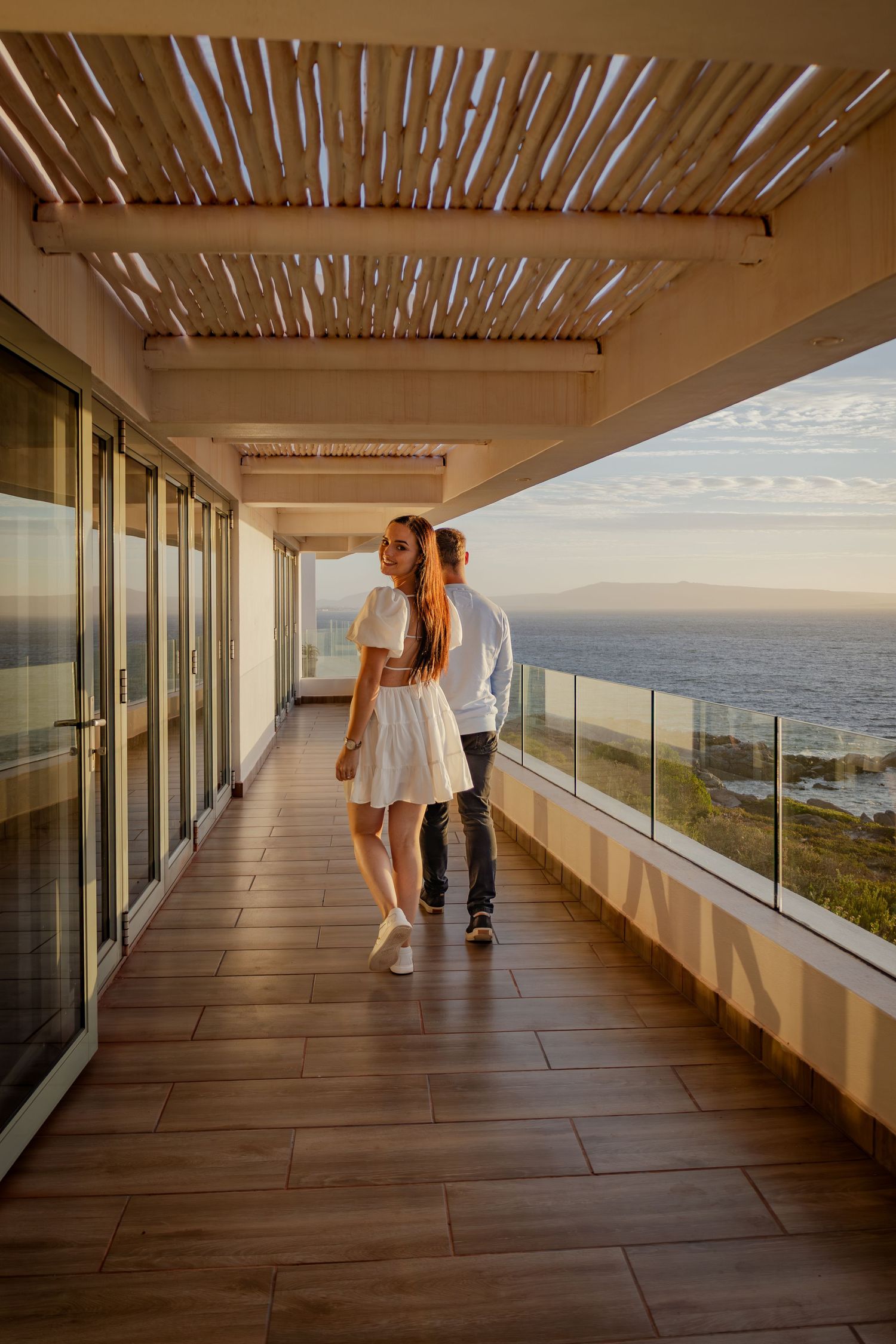 Couple posing playfully on a balcony and showing the engagement ring