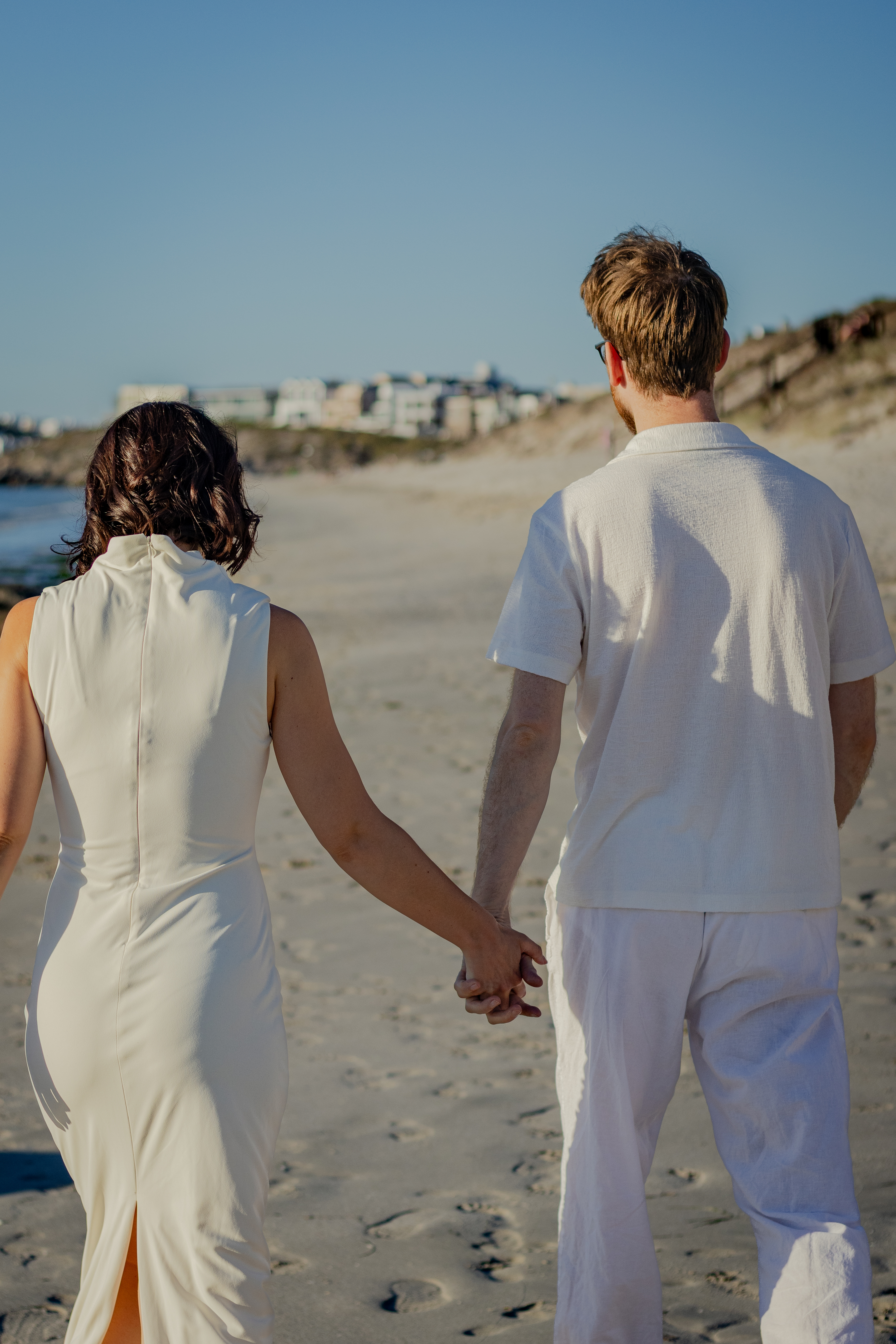 Couple walking hand in hand from behind