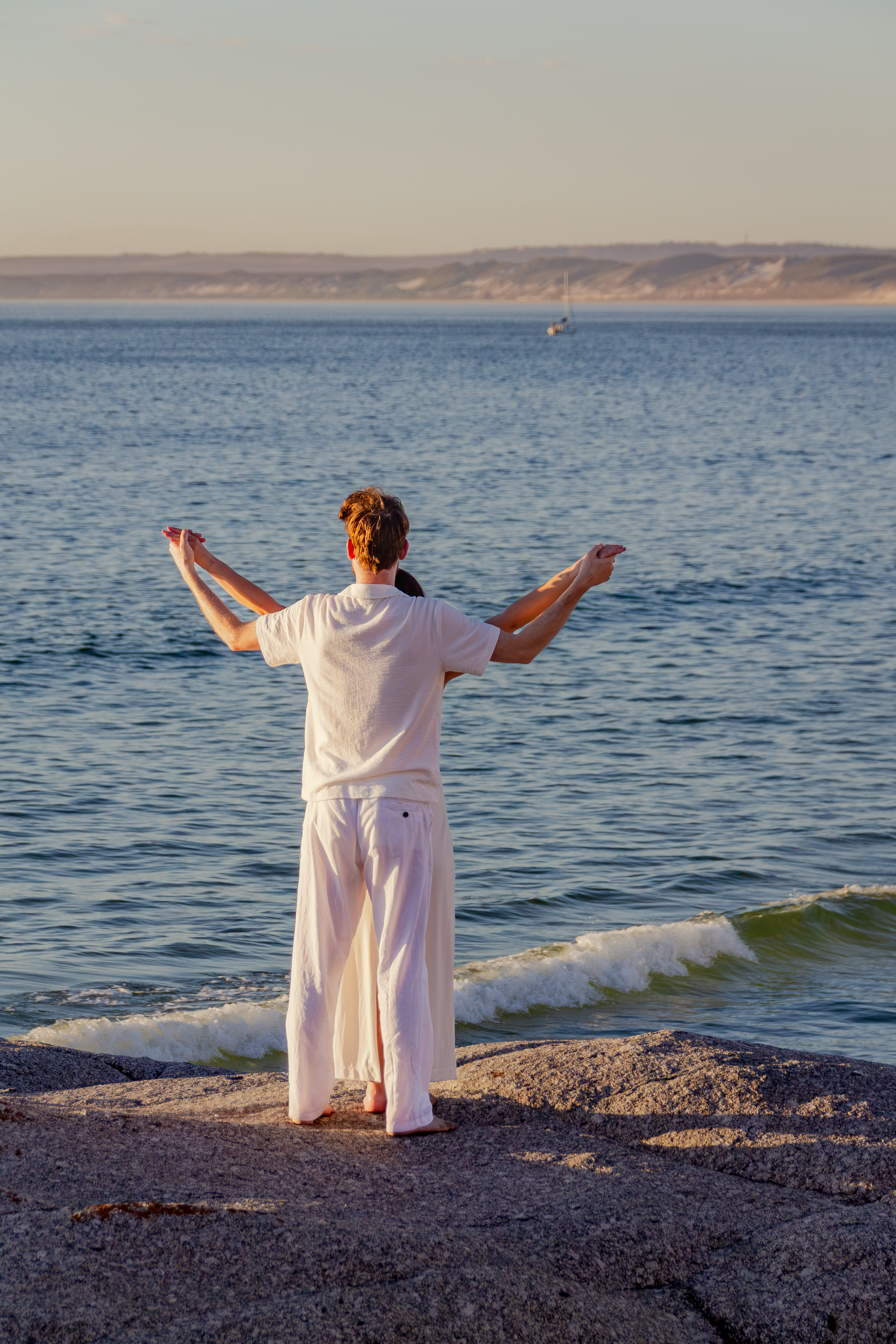 Couple holding hands with the sea behind them