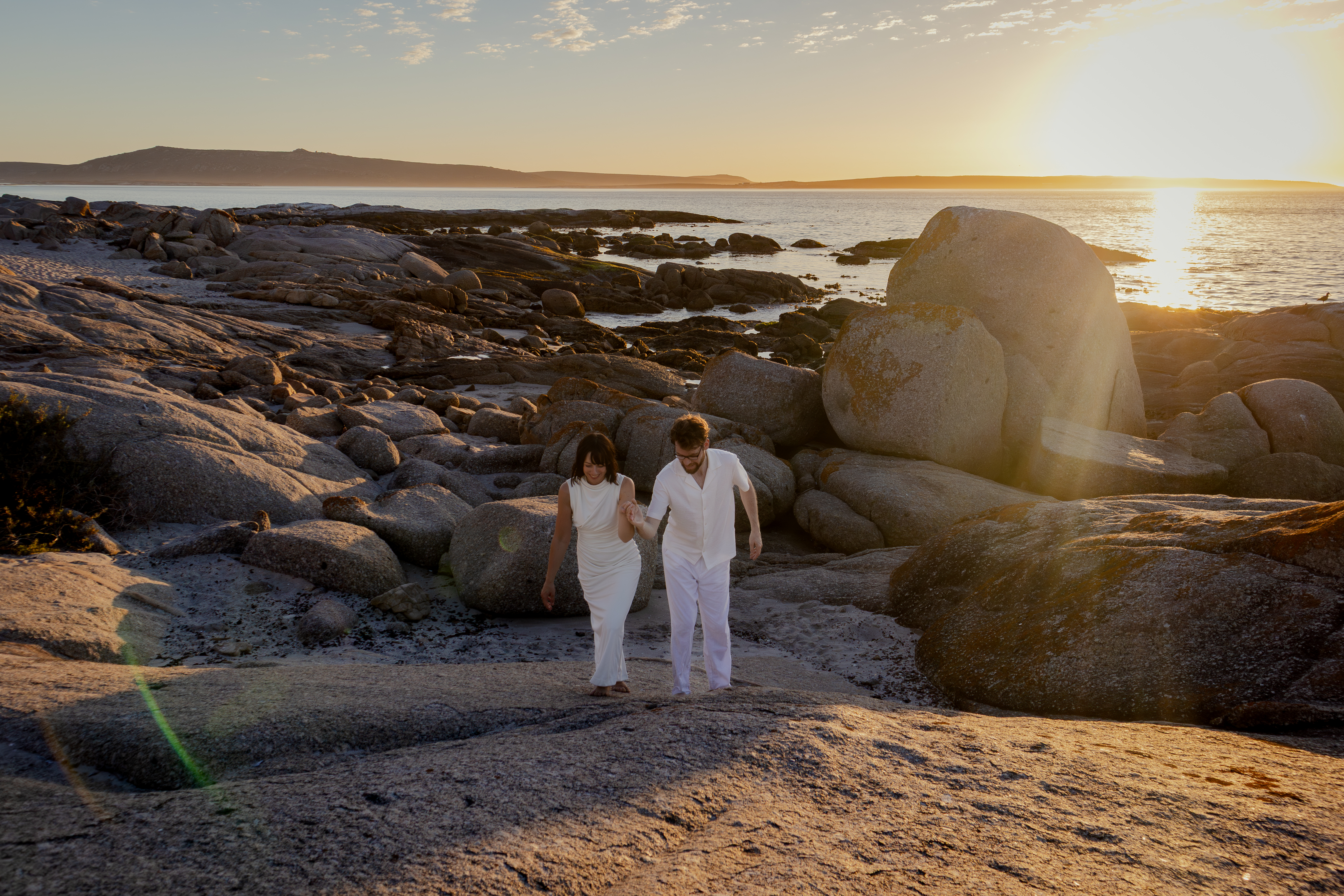 Couple embracing against a bright sunset sky