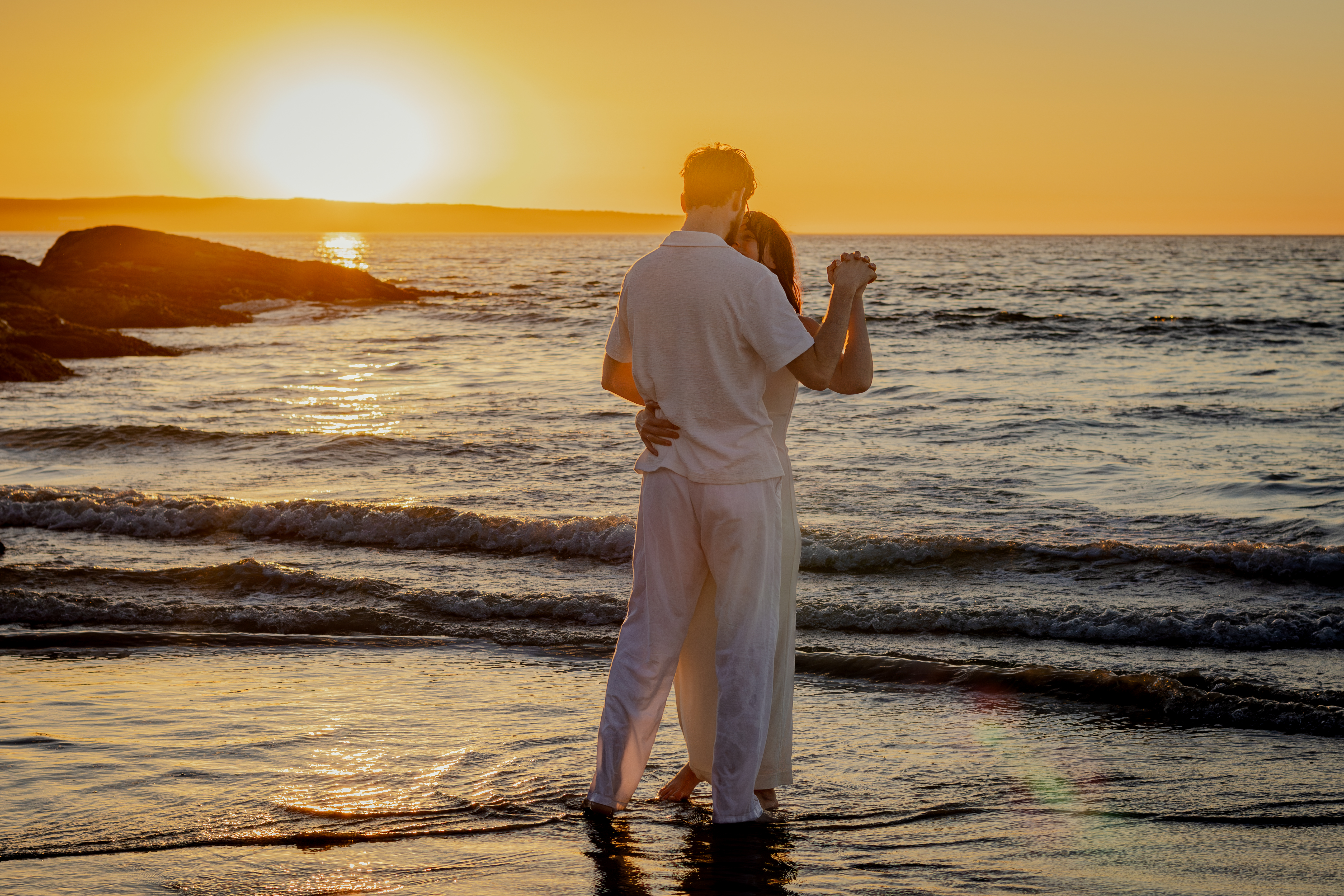 Couple standing among the shoreline rocks