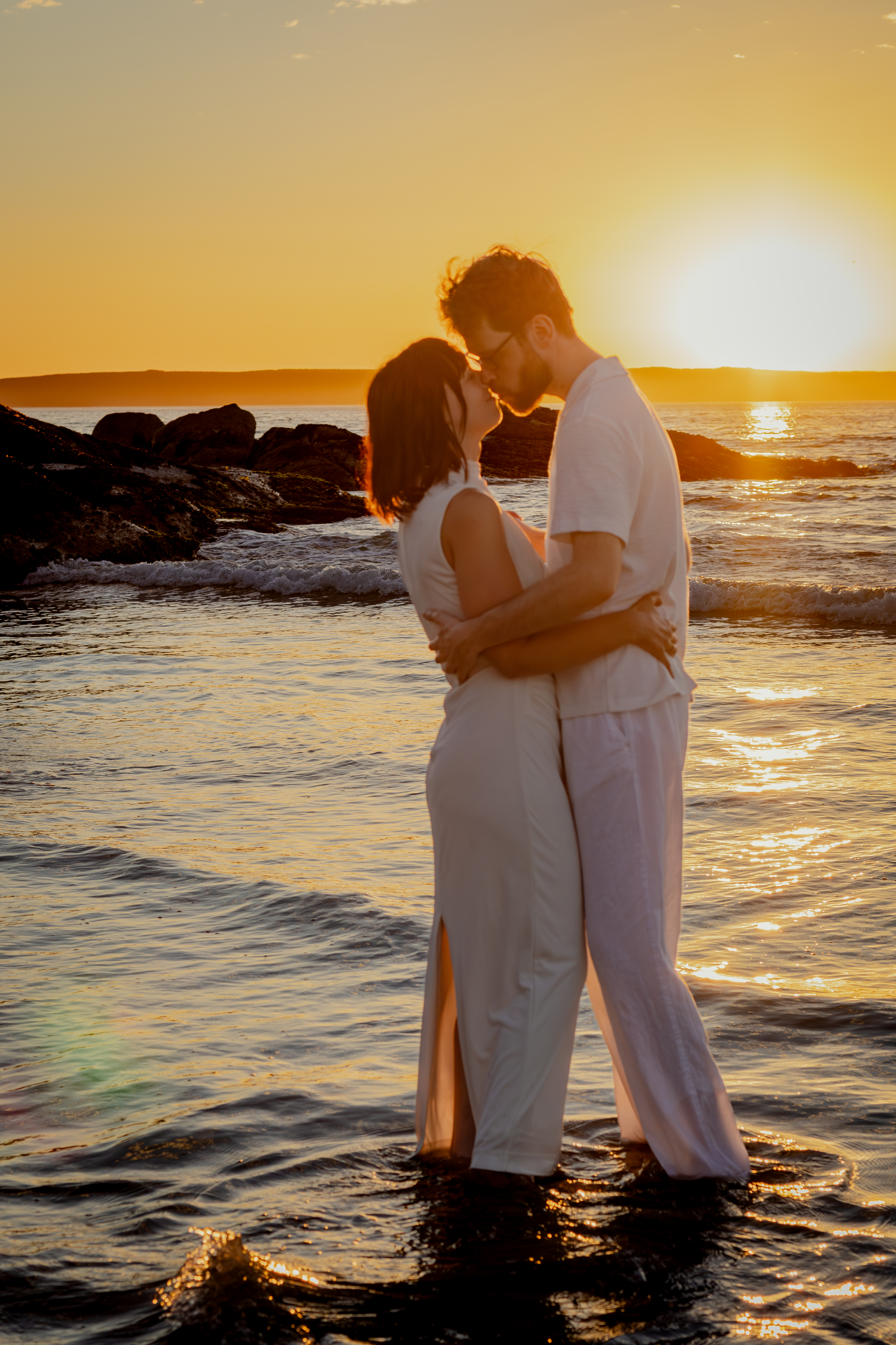 Couple embracing at sunset by the rocks