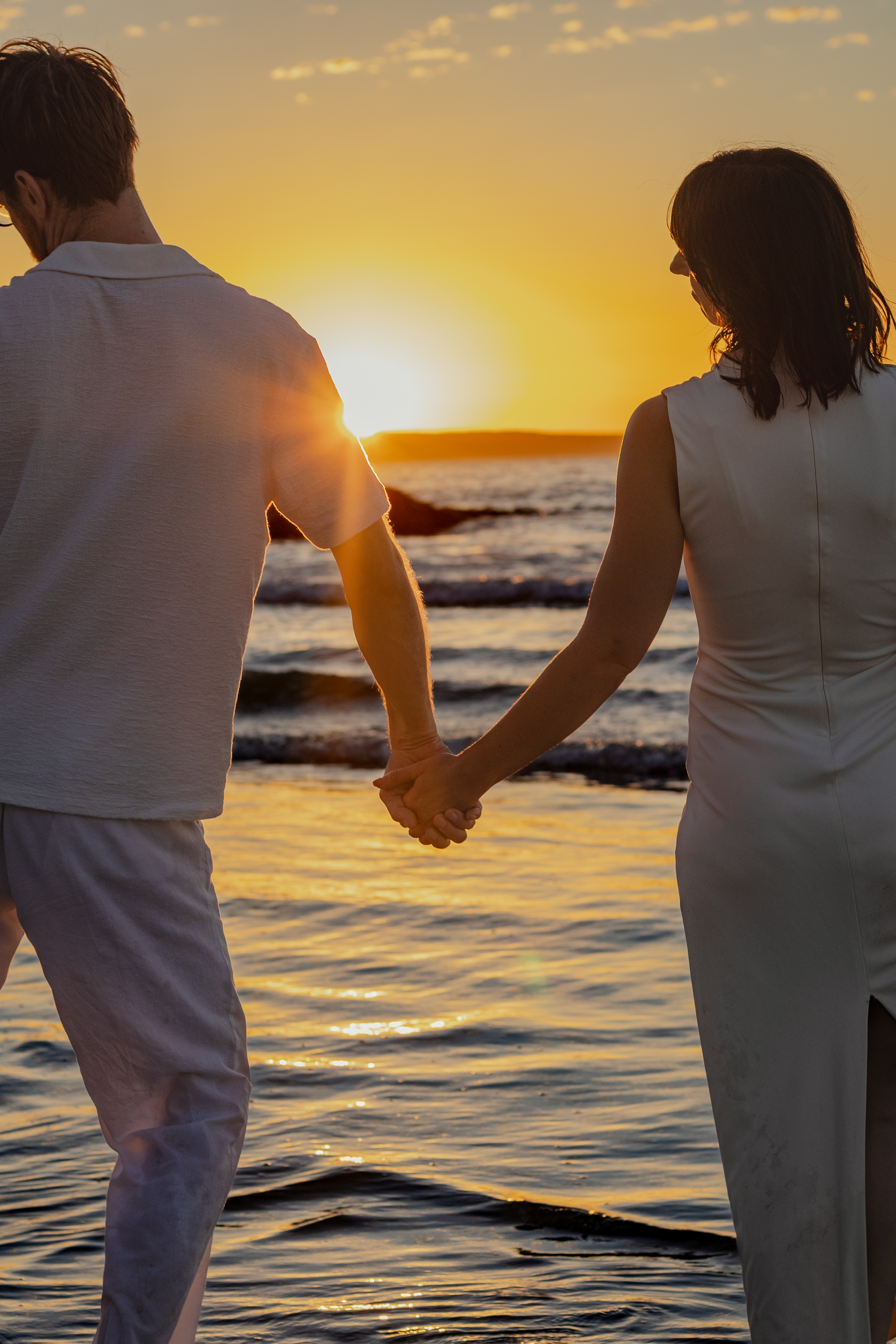 Couple standing together on the shoreline at dusk