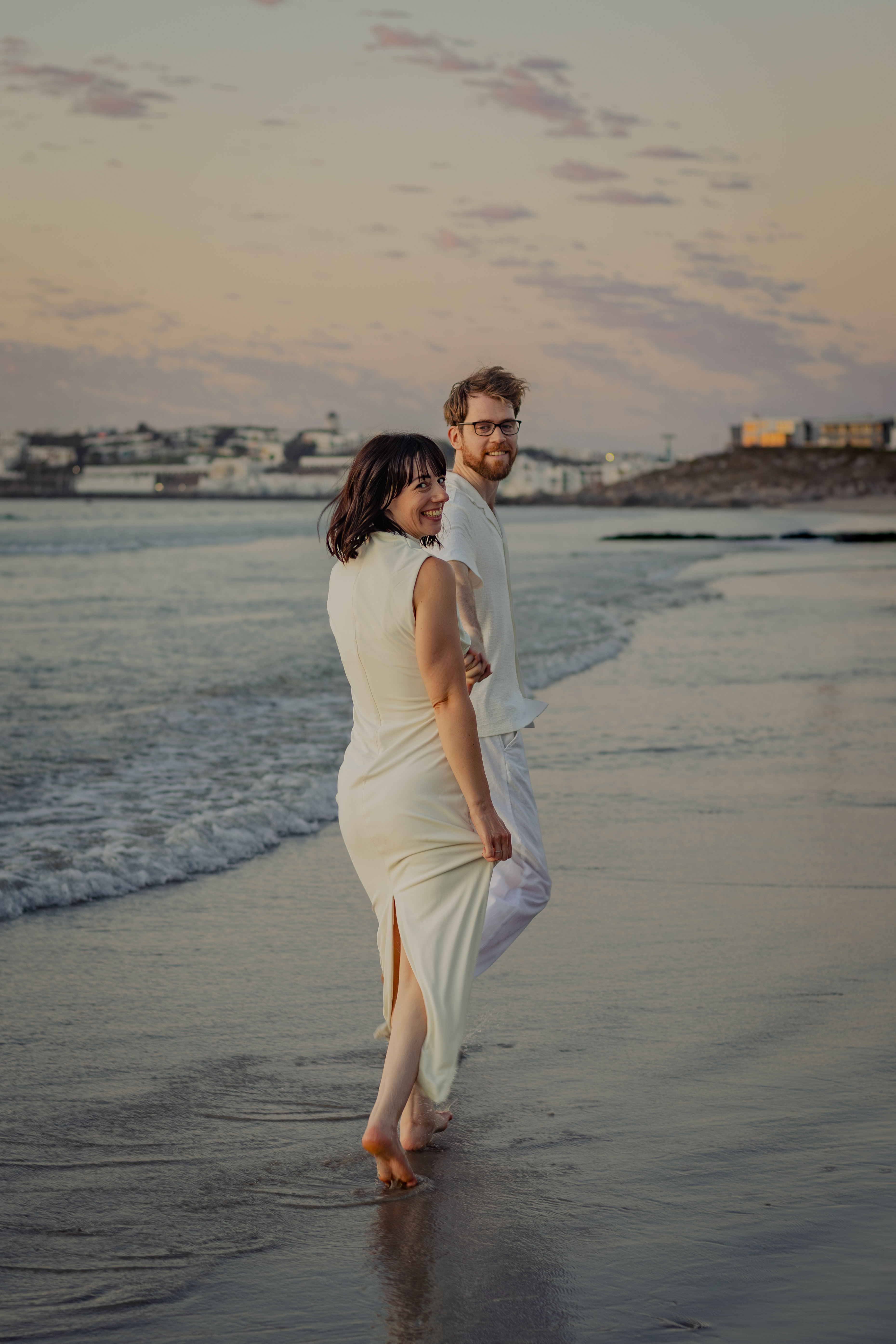 Bride standing alone on the beach at sunset