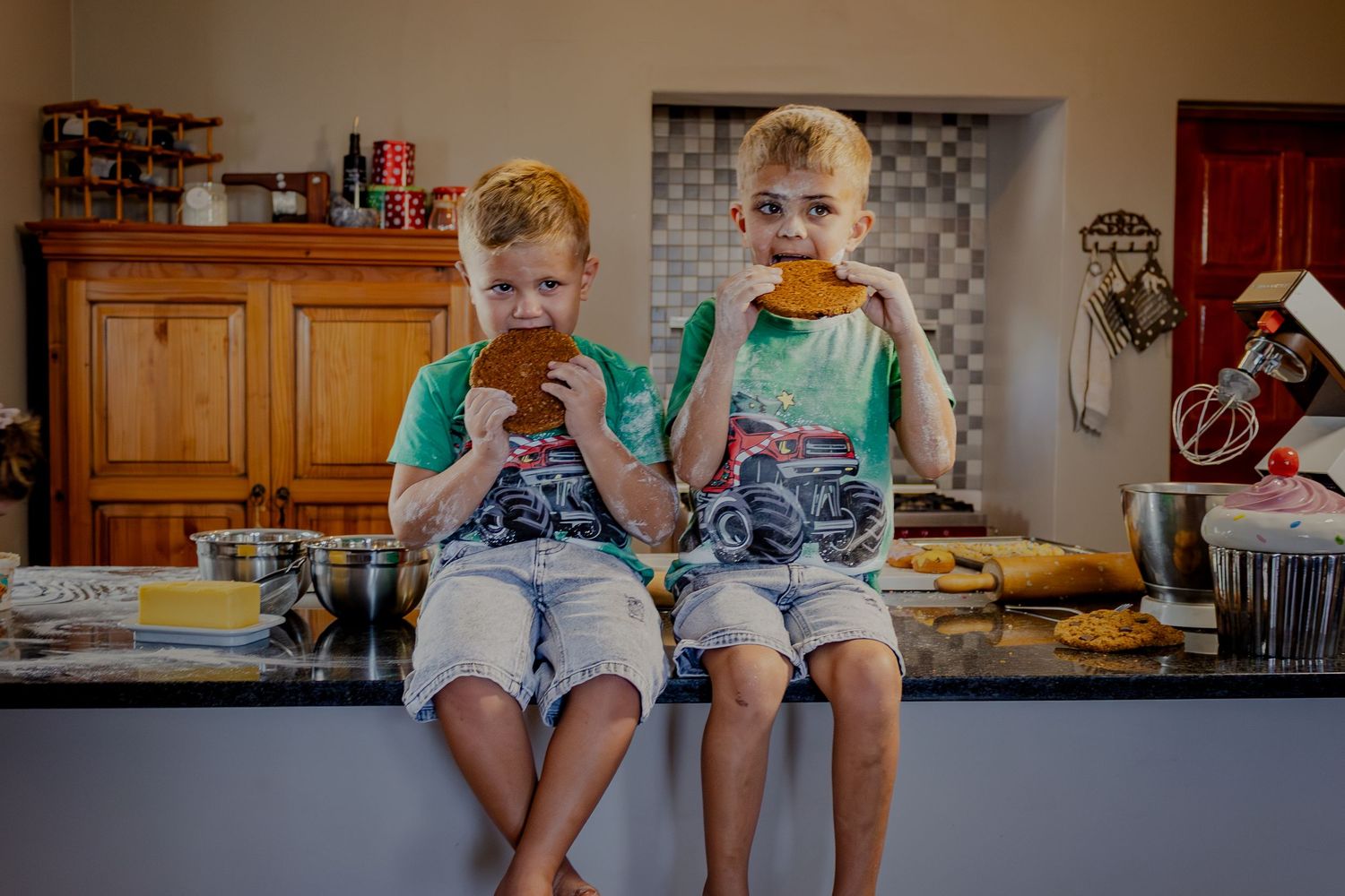 Children seated on the kitchen counter with baking tools